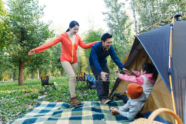 Glückliche Eltern betrachten entzückende Kinder, die sich im Zelt im Wald ausruhen — Stockfoto
