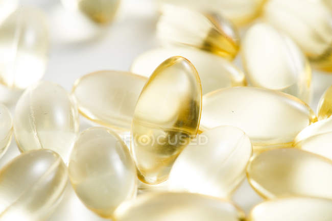 Primo piano di sparse pillole gialle sulla superficie bianca — Foto stock