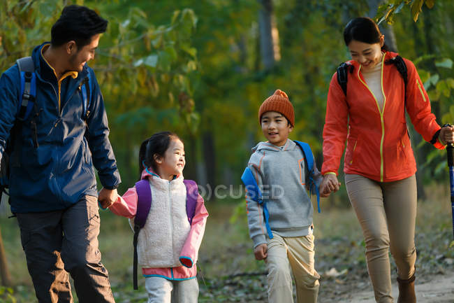 Feliz joven asiático familia con dos niños senderismo en bosque - foto de stock