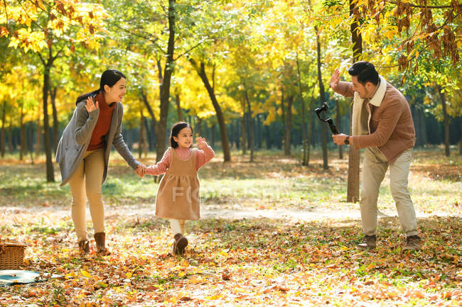 Щасливий азіатський батько робить фотографію дочки та дружини зі смартфоном у автономному парку — стокове фото