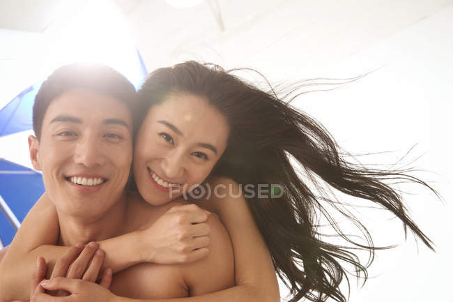 Happy asian boyfriend giving piggyback to girlfriend on beach — Stock Photo