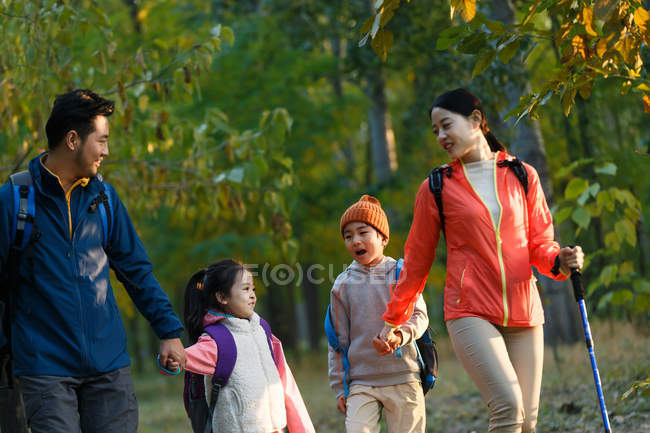 Счастливая молодая семья с двумя детьми гуляет в лесу — стоковое фото