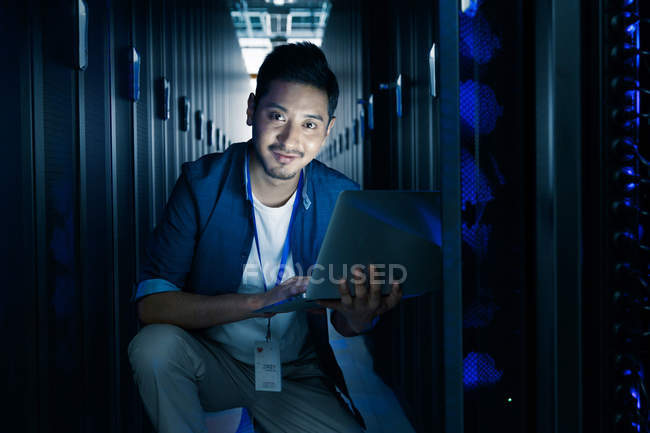 Homem usando computador portátil e sorrindo para a câmera na inspeção da sala de manutenção — Fotografia de Stock