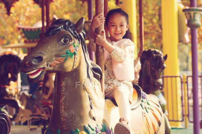 Entzückend glückliches kleines Mädchen, das mit Karussell spielt und in die Kamera lächelt — Stockfoto