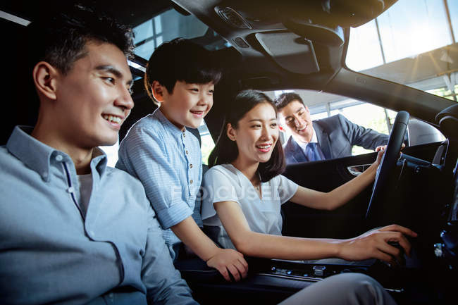 Asian family with kid testing car at showroom — Stock Photo