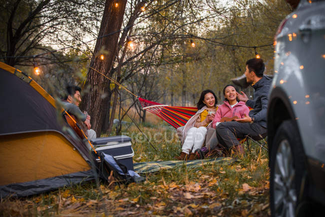 Man playing guitar for asian friends in autumnal forest — Stock Photo