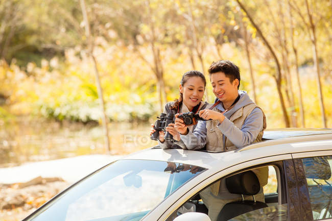 Азиатская пара смотрит на камеру в автомобиле в осеннем лесу — стоковое фото