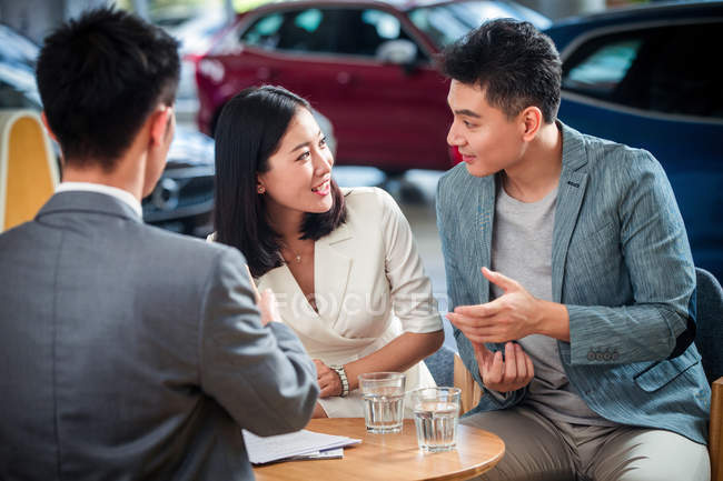 Asiatisches Paar kauft Auto im Showroom und redet miteinander — Stockfoto