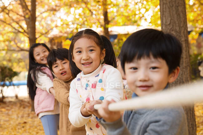 Чарівні щасливі китайські діти грають на буксирі війни в осінньому парку — стокове фото
