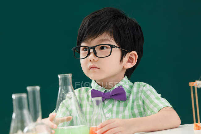 Adorable asian schoolboy looking away at chemistry class at school — Stock Photo