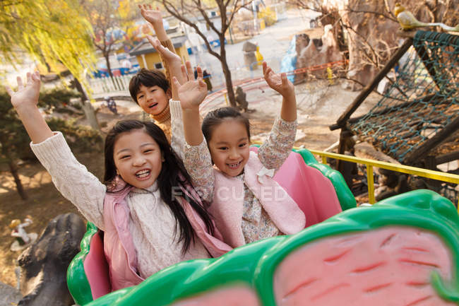 Menino feliz e meninas brincando juntos na montanha russa no parque — Fotografia de Stock