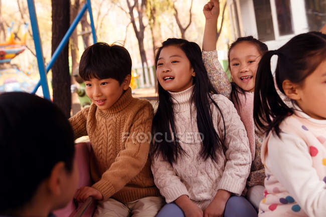 Five adorable happy asian kids having fun on carousel in autumnal park — Stock Photo