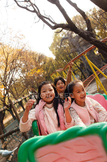 Щасливий хлопчик і дівчата сидять разом на роликових гірках в парку — стокове фото