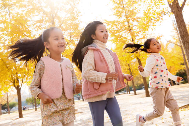 Трое восхитительных счастливых детей бегают в осеннем парке — стоковое фото