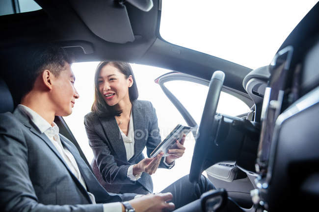 Asian businessman buying new car and talking to seller at showroom — Stock Photo