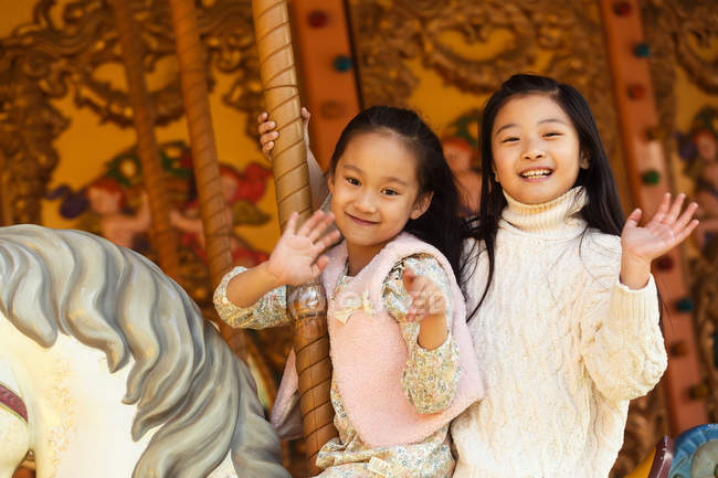 Adorable happy little girls playing with carousel — Stock Photo