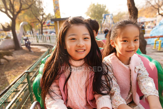 Счастливые девушки играют вместе на американских горках в парке — стоковое фото
