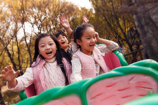 Heureux asiatique enfants assis ensemble sur roller coaster dans parc — Photo de stock