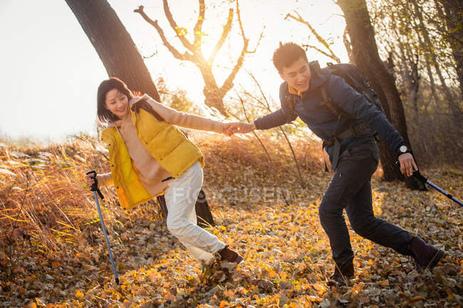 Азиатская пара, держащаяся за руки и путешествующая в осеннем лесу — стоковое фото