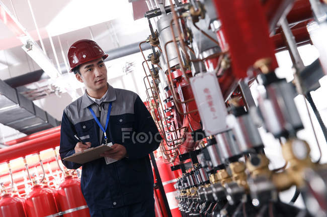 Professional male engineer in hard hat working in the factory fire control room inspection — Stock Photo