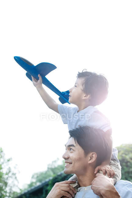 Счастливы отец и сын, играющие с игрушечным самолетом на дворе — стоковое фото