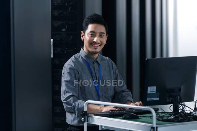 Pessoal técnico usando computador e sorrindo para a câmera na inspeção da sala de manutenção — Fotografia de Stock
