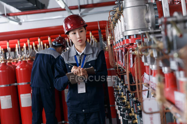 Ingegneri professionisti di sesso maschile e femminile in cappelli duri che lavorano nell'ispezione della sala antincendio della fabbrica — Foto stock