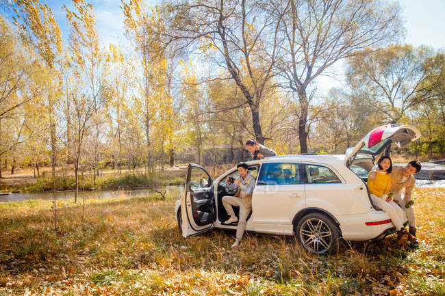 Maschio e femmina asiatico amici seduta in auto in autunno foresta — Foto stock