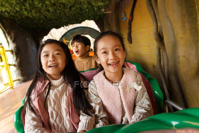 Счастливые мальчики и девочки, играющие вместе на горках в парке — стоковое фото