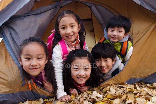 Fünf entzückende asiatische Kinder blicken aus einem Zelt im herbstlichen Park in die Kamera — Stockfoto