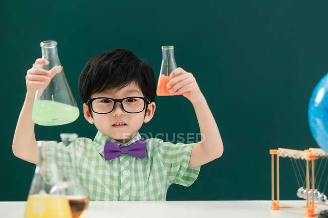 Adorable asiatique écolier tenant ampoules à chimie classe à l'école — Photo de stock