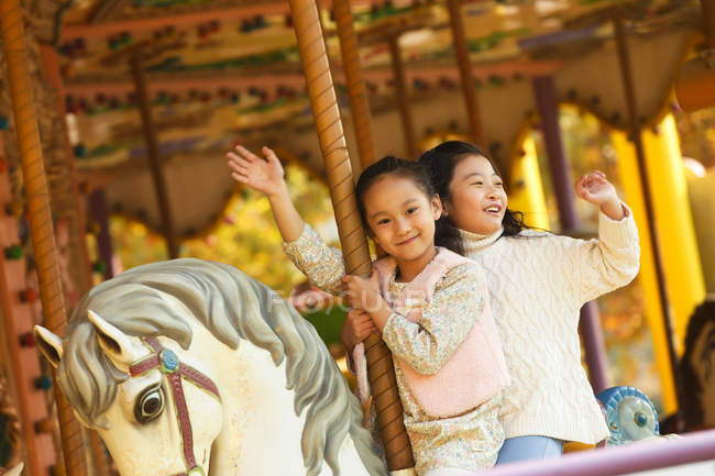 Чарівні щасливі маленькі дівчата грають з карусель — стокове фото