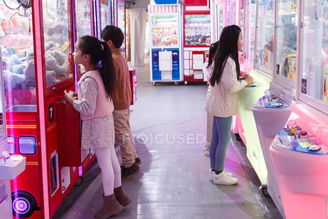 Menino feliz e meninas brincando juntos no salão de jogos — Fotografia de Stock