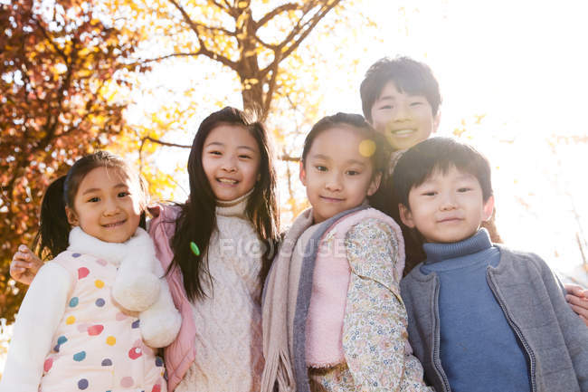 П'ять чарівних азіатських дітей обіймаються і дивляться на камеру в автономному парку — стокове фото