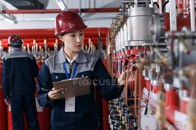 Ingegneri professionisti di sesso maschile e femminile in cappelli duri che lavorano nell'ispezione della sala antincendio della fabbrica — Foto stock