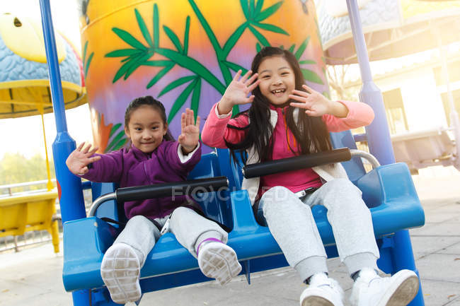 Niñas felices jugando juntos en la montaña rusa en el parque - foto de stock