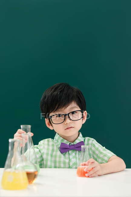 Adorable asiático escolar celebración bulbos en química clase en la escuela - foto de stock