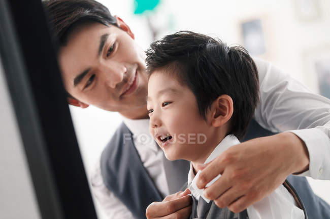 Избирательный фокус веселого азиатского отца, носящего сына дома — стоковое фото