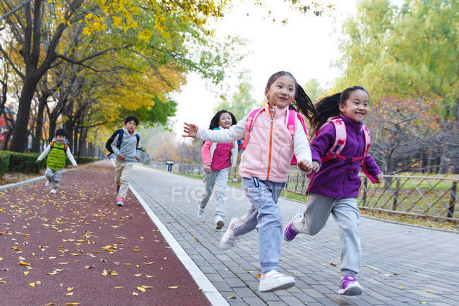 Cinco adorável asiático crianças correndo na estrada no outonal parque — Fotografia de Stock