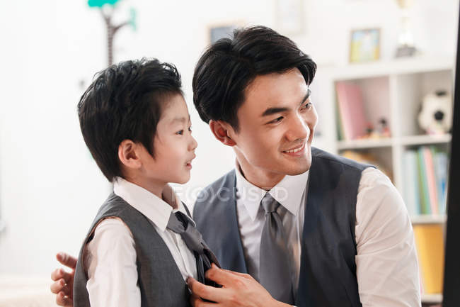Asiático padre y preescolar hijo preparación para el evento y el uso de trajes en casa - foto de stock