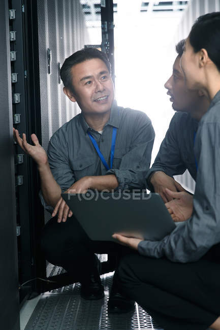 Технічний персонал, що працює з портативним комп'ютером під час огляду приміщення для обслуговування — стокове фото
