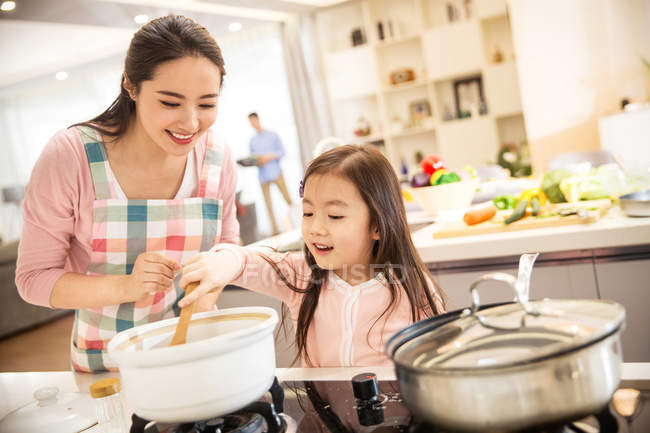 Happy asian mother and daughter cooking together in kitchen — Stock Photo