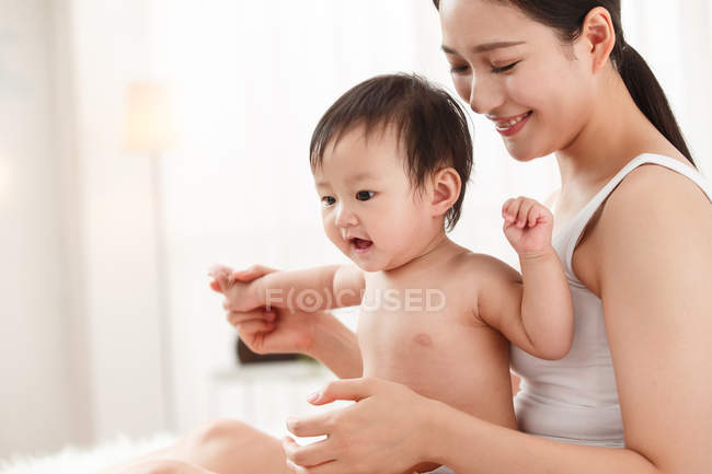 Feliz jovem mãe sentada com bebê adorável em casa — Fotografia de Stock