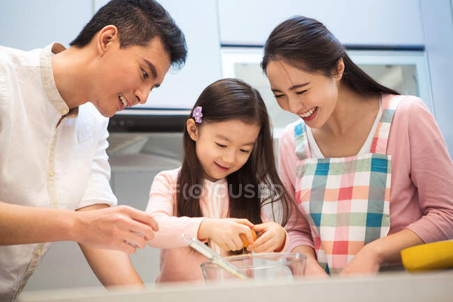 Счастливая семья с одним ребенком готовит вместе на кухне — стоковое фото