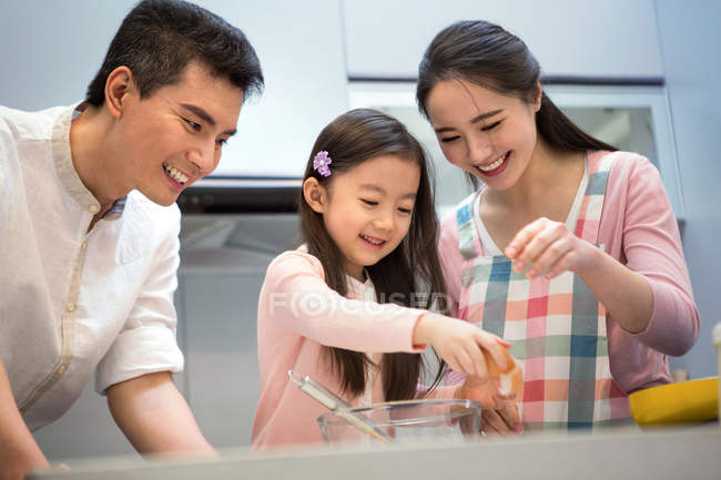Счастливая семья с одним ребенком готовит вместе на кухне — стоковое фото