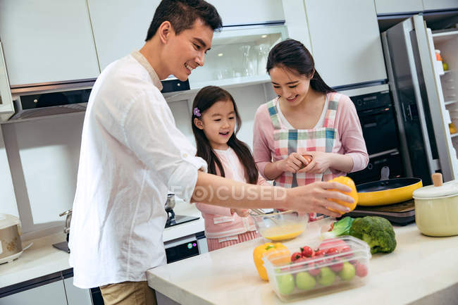 Счастливые родители с очаровательной маленькой дочерью, готовящей вместе на кухне — стоковое фото