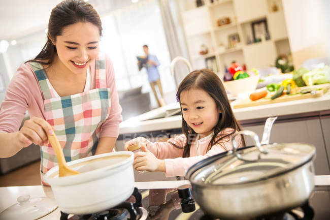 Happy asian mother and daughter cooking together in kitchen — Stock Photo