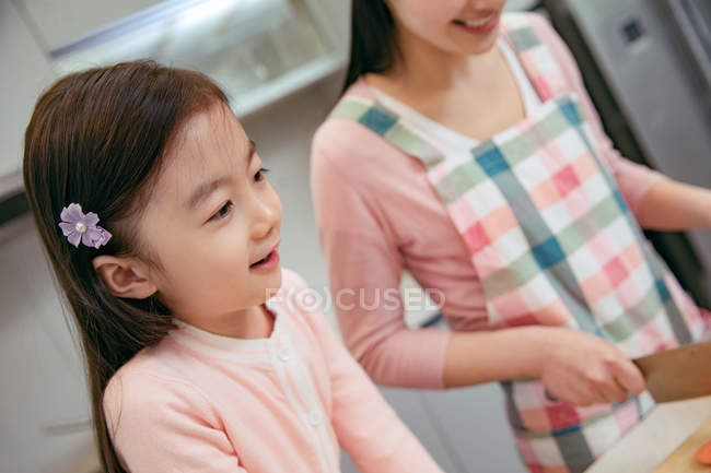 Обрезанный снимок очаровательного азиатского ребенка приготовления пищи с матерью на кухне — стоковое фото