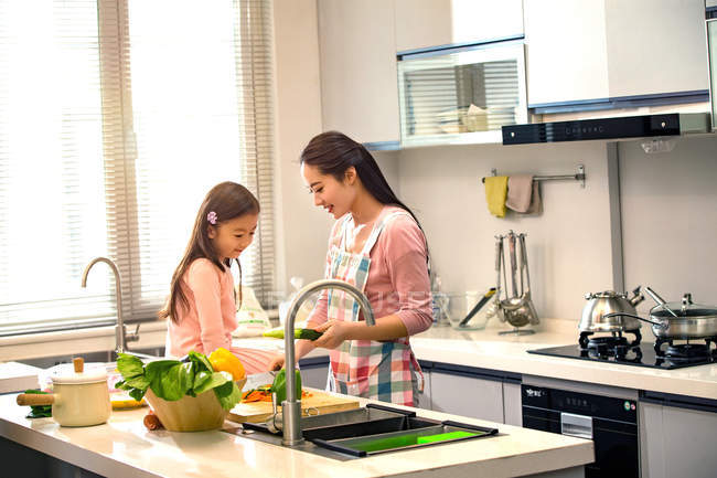 Glückliche junge Mutter und süße kleine Tochter kochen zusammen in der Küche — Stockfoto