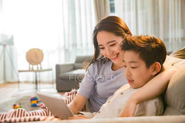 Happy asian mother with son using digital tablet together at home — Stock Photo